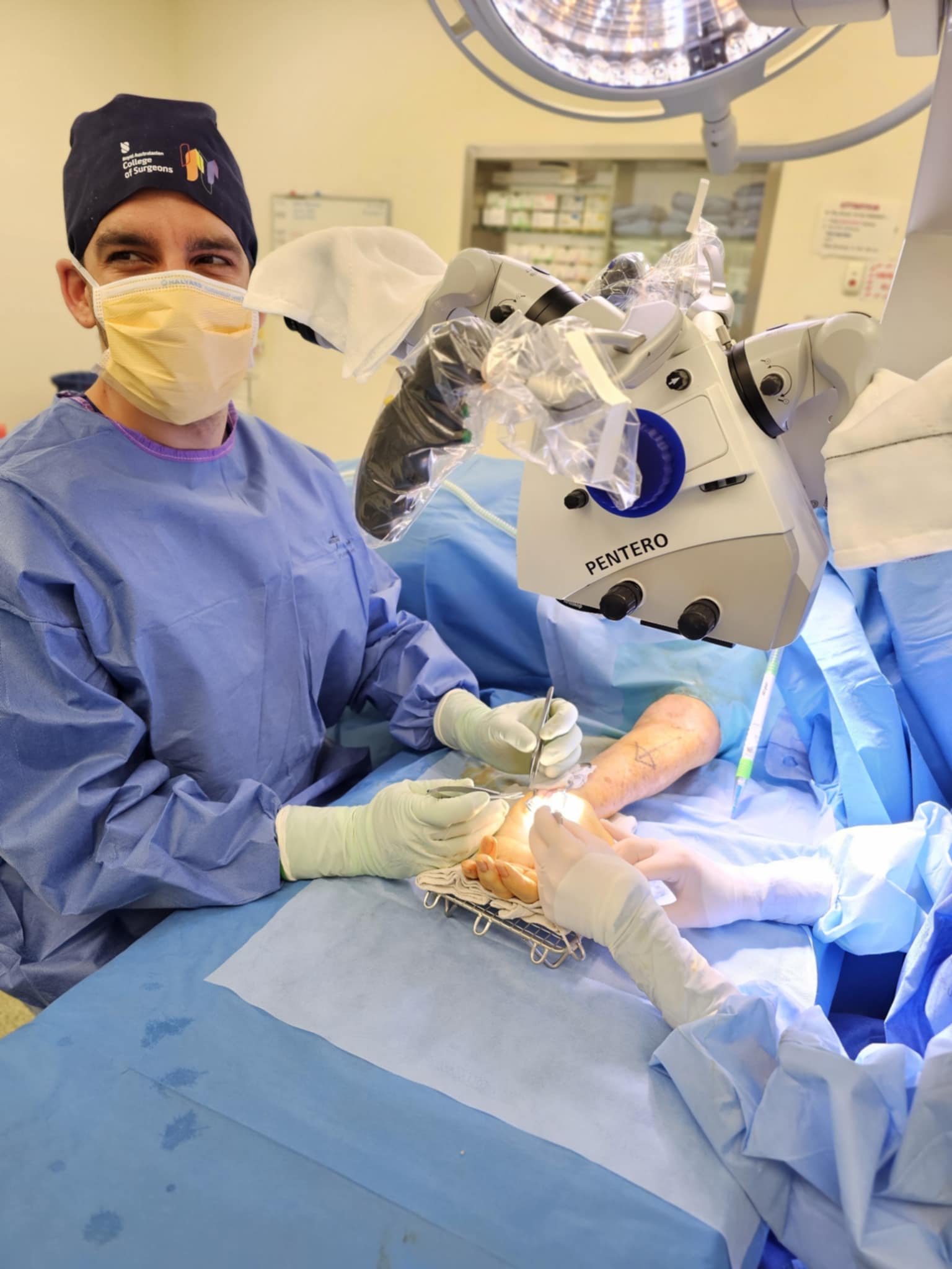 Dr Parr smiling while performing surgery on a patient's hand in a sterile environment